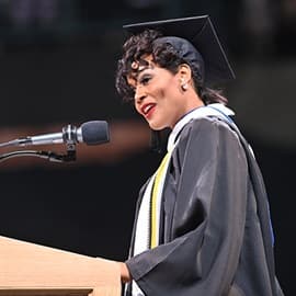 Sonnecia Williams standing at a podium in front of a microphone and delivering her SNHU Commencent address.