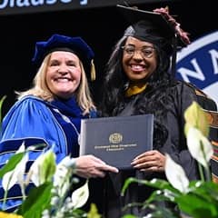 SNHU President Lisa Marsh Ryerson and graduating student holding diploma cover at commencement ceremony.