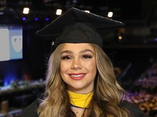 Tiare Hazen, who earned her bachelor's in business administration from SNHU in 2023, wearing her cap and gown and holding her diploma.