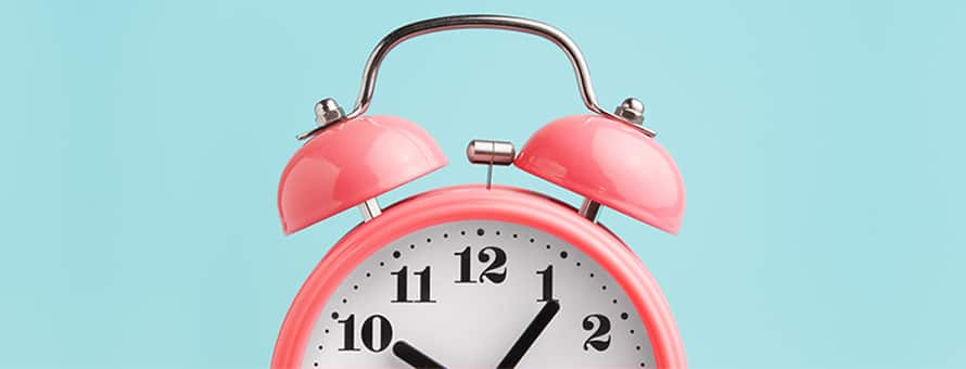 The top half of a pink analog clock used for time management, set against a blue background