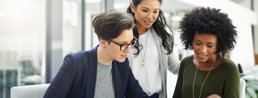 Three business professionals reviewing a presentation on a laptop.