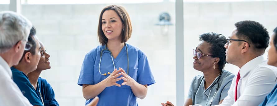 A medical professional with a stethoscope having a discussion with others in the medical field