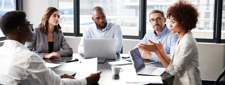 A criminal justice professional working in a corporate setting and communicating with four colleagues in a meeting.