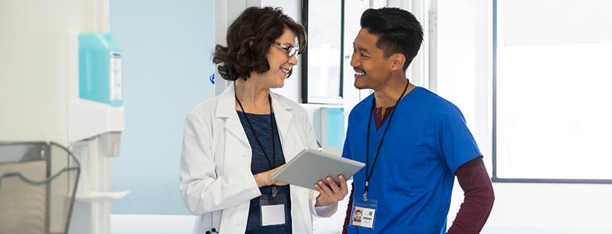 Two healthcare professionals with different types of master’s degrees discussing a chart in a healthcare facility.