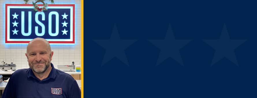 Michael Shimkus in front of a USO banner next to a blue graphic with stars on it