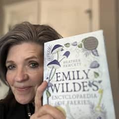 Vickie McCullough, an MED online instruction adjunct professor at SNHU, holding "Emily Wilde's Encyclopedia of Faeries" by Heather Fawcett.