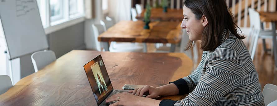 A healthcare student sitting at a table, participating in a webinar on her laptop.