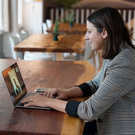 A healthcare student sitting at a table, participating in a webinar on her laptop.