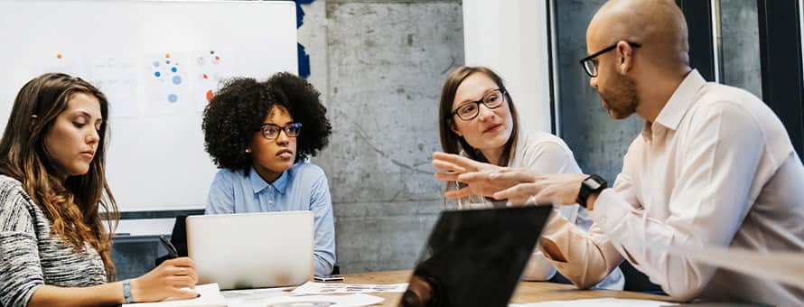 A sociologist in a conference room, explaining a study to three colleagues during a meeting.