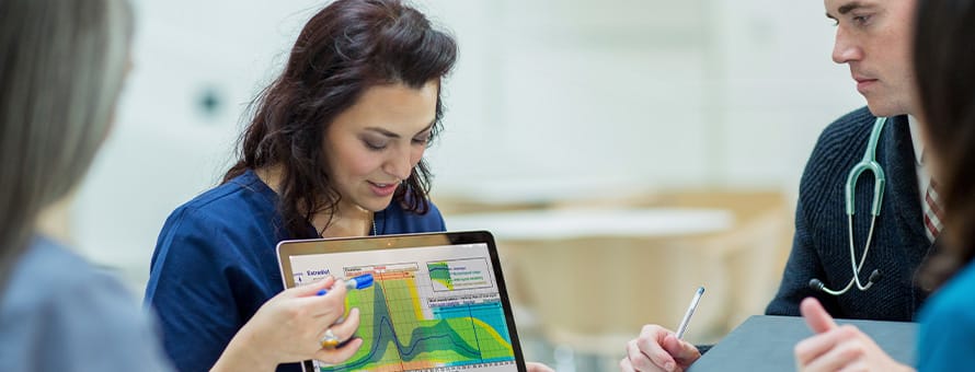 A professional with an MPH degree walking three cross-departmental teammates through a graph on her laptop.