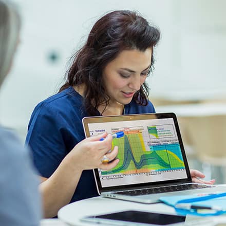 A professional with an MPH degree explaining a graph on her laptop to some public health colleagues.