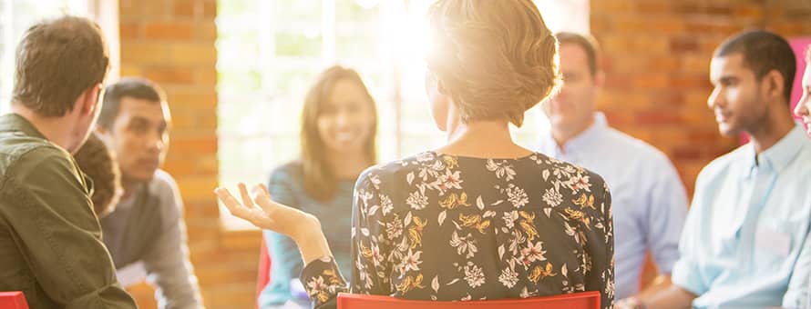 Eight professionals sitting in a circle while one describes what organizational leadership is.