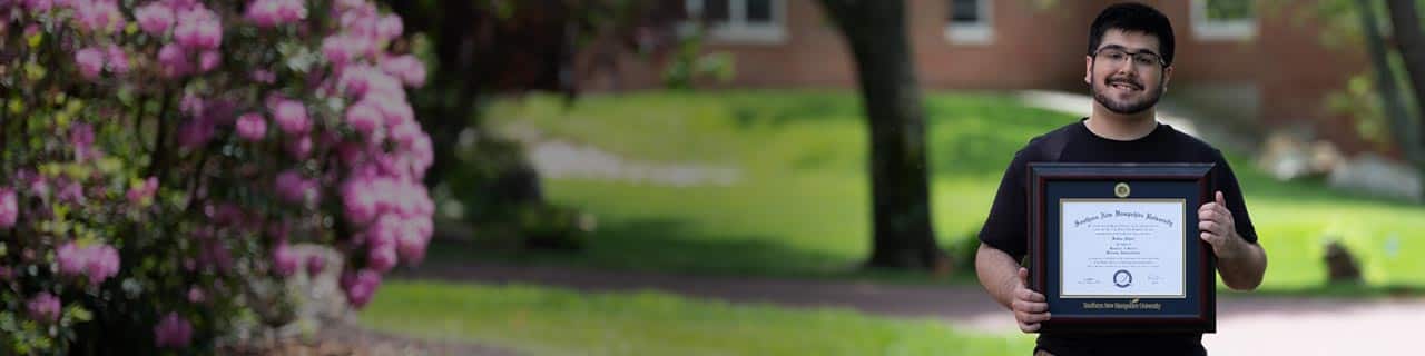 A SNHU student holding his degree