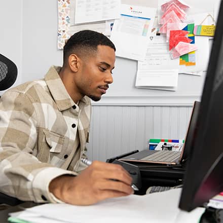  Keyon Tuiteleleapaga, an SNHU master's in psychology alum, sitting at a desk working on his desktop. 