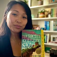 Wreachell Duaqui-Nguyen, an SNHU graduate with a bachelor's and master's in data analytics, holding "The House in the Cerulean Sea" by TJ KLUNE.