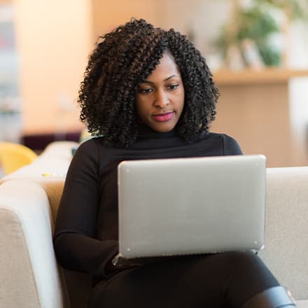 A woman sitting and writing an effective resume on a laptop