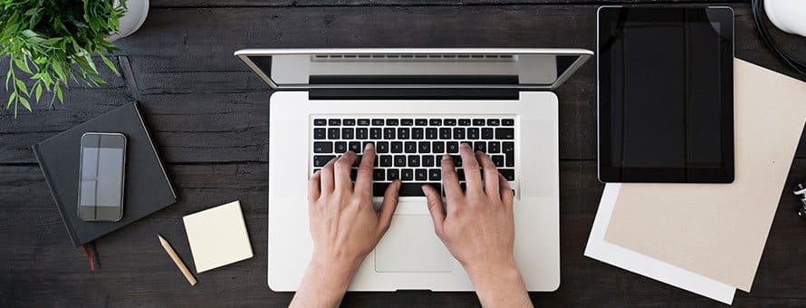 Overhead view of someone sitting at a desk typing on a laptop