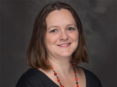 Zuzana Buzzell, associate dean of online business programs at Southern New Hampshire University, wearing a dark shirt and long, multi-colored necklace.