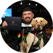 U.S. Army veteran, SNHU graduate and Massachusetts resident Jereme West holding his service dog and SNHU diploma.